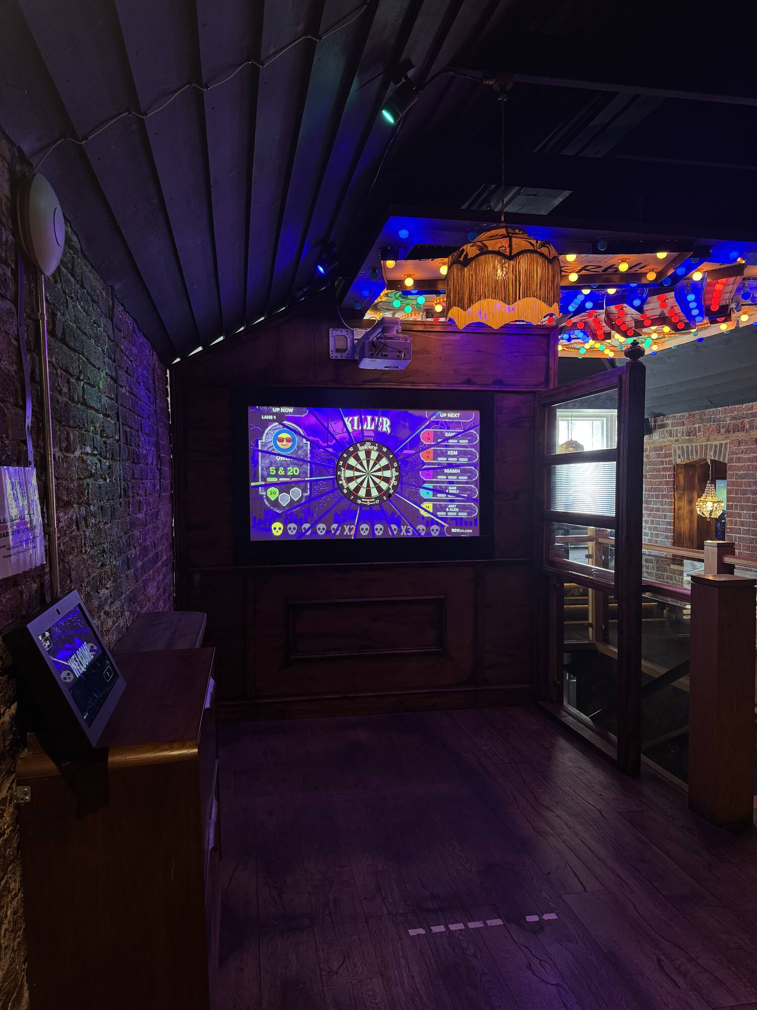 The interactive dartboard lit up against exposed brick and festoon lights