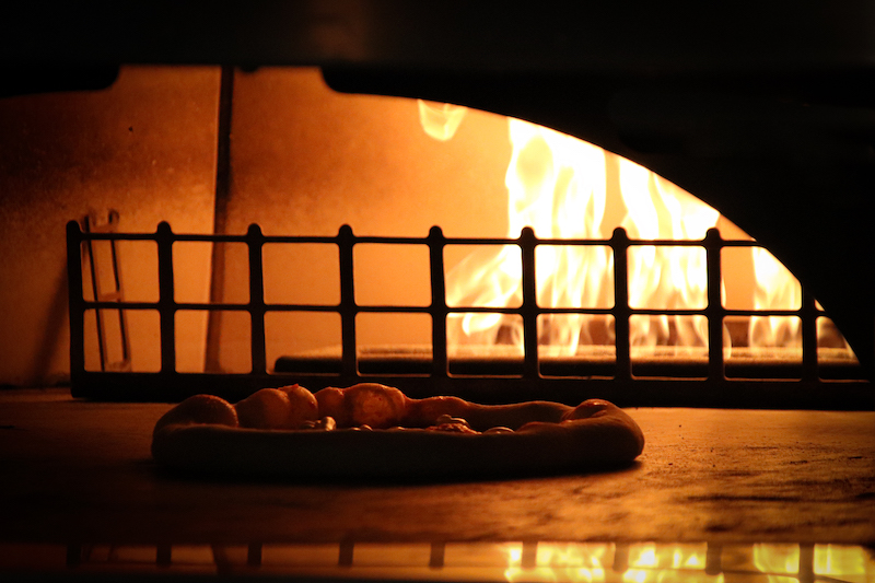 A pizza baking in the wood-fired oven