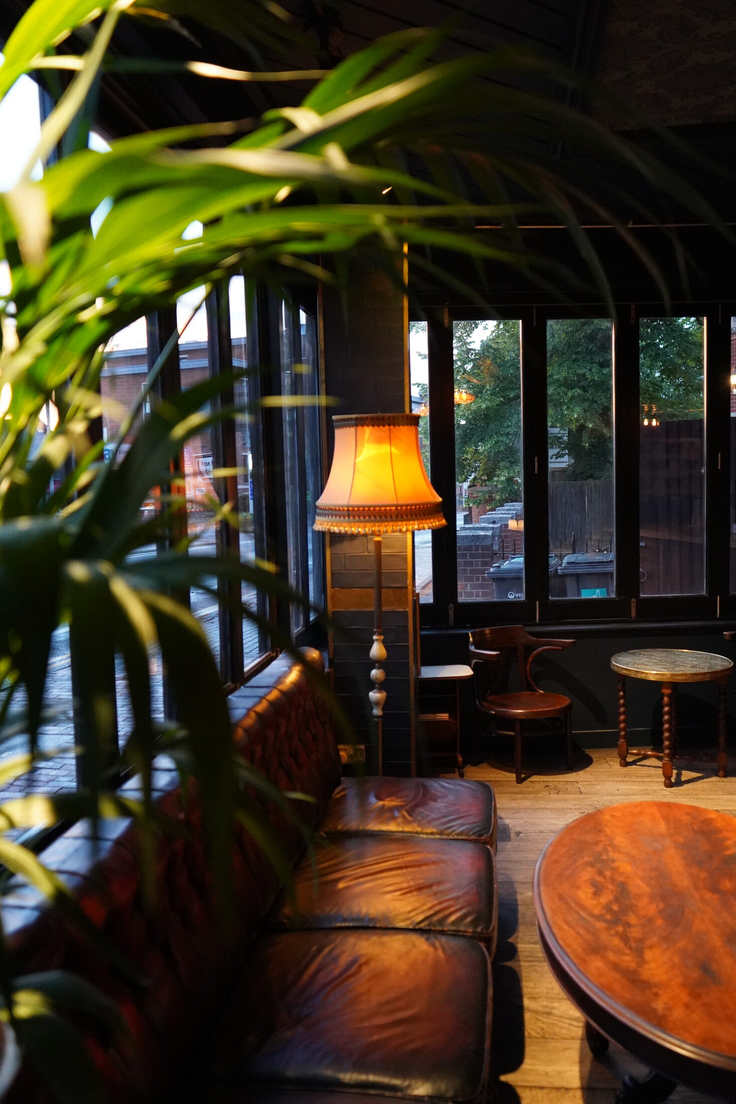 Leather seating by the windows with a glowing lamp and leafy plants